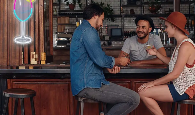 Three people were chatting together on the bar, and there was a neon wineglass logo on the wall for business